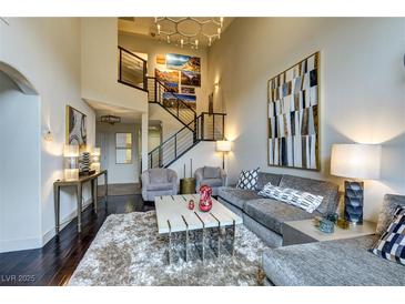 Bright living room with soaring ceilings, art accents, modern staircase, and plush furniture at 10210 Juniper Creek Ln, Las Vegas, NV 89145