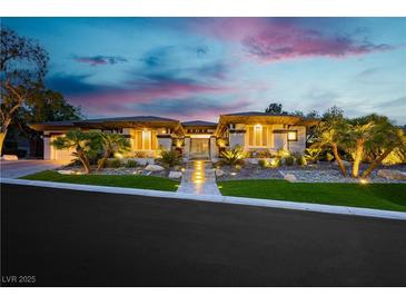 Stunning single story home with lush landscaping, pathway, and unique architecture highlighted at twilight at 19 Isleworth Dr, Henderson, NV 89052
