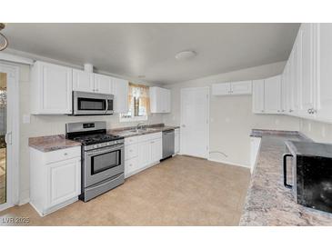 Bright kitchen features white cabinets, granite countertops, and stainless steel appliances at 3709 Perliter Ave, North Las Vegas, NV 89030