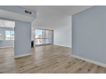 Bright living room featuring wood flooring, modern light-blue paint, a fireplace, and sliding glass doors to the balcony at 725 N Royal Crest Cir # 237, Las Vegas, NV 89169