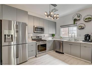 Modern kitchen featuring stainless steel appliances, gray cabinets, and decorative lighting at 10270 Gilmore Canyon Ct # 202, Las Vegas, NV 89129