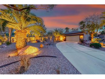 Desert landscaped home with a long driveway lined with palm trees against a colorful sunset at 1983 Songbird Ct, Henderson, NV 89012