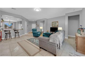 Open-concept living room with neutral tones, tile floors, and modern furnishings at 2709 Rue Montpellier Ave, Henderson, NV 89044