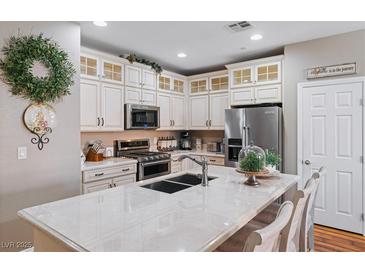 Bright kitchen with white cabinets, stainless steel appliances and large center island with marble countertop at 3185 Mura Del Prato Ave, Henderson, NV 89044
