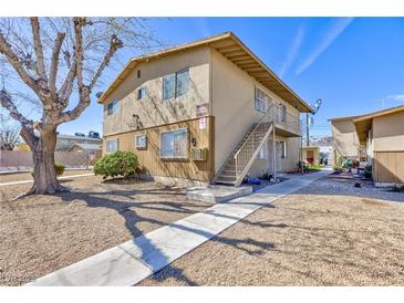 Two-story tan apartment building features a sidewalk and minimal landscaping at 3821 1/2 Daisy St # 26, Las Vegas, NV 89119