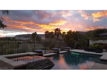 Inviting pool with water features, set against a backdrop of a vibrant sunset and palm trees at 11241 Golden Chestnut Pl, Las Vegas, NV 89135