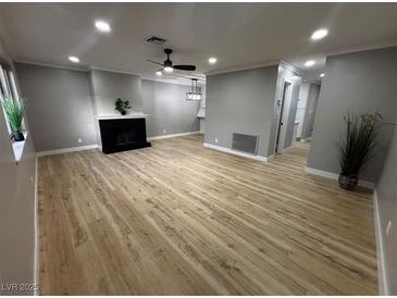 Bright living room with a decorative fireplace, ceiling fan, and modern light fixture at 150 Greenbriar Townhouse Way, Las Vegas, NV 89121