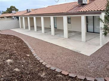 Spacious covered back patio with large support posts, concrete flooring, and decorative rock landscaping at 1608 Joshua Tree Ct, Las Vegas, NV 89108