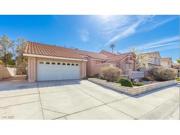 Charming single-story home featuring a two-car garage, well-maintained landscaping, and a tile roof on a sunny day at 3040 Ocean Port Dr, Las Vegas, NV 89117