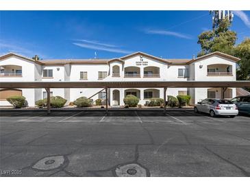 White two-story condo building featuring covered parking and well-maintained landscaping at 5655 E Sahara Ave # 1060, Las Vegas, NV 89142