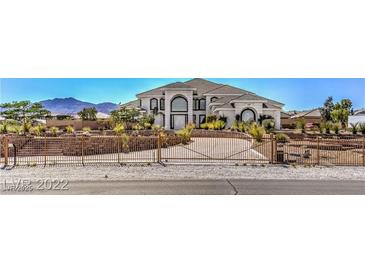 Beautiful two-story home with large windows, arched doorway, desert landscaping and gated entrance at 7025 N Eula St, Las Vegas, NV 89149