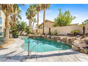 Beautiful pool with tropical landscaping, rock border and metal handrail creates a backyard oasis at 124 Beach Oak Ave, Henderson, NV 89002