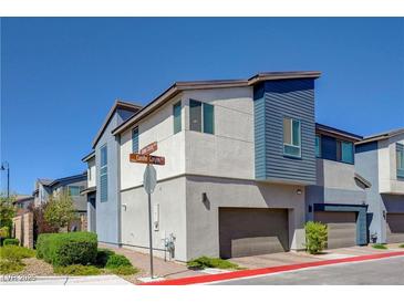 Modern two-story townhome with blue and white exterior, featuring an attached garage and manicured landscaping at 2685 Conifer Canyon St, Henderson, NV 89044