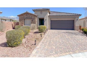 Inviting single-story home with a stone facade, desert landscaping and a paver driveway leading to a two-car garage at 5555 E San Pietro Dr, Pahrump, NV 89061