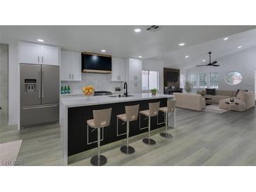 Modern kitchen with stainless steel appliances, a large island with seating, and an open floor plan at 7413 Turtle Dove Ct, Las Vegas, NV 89129