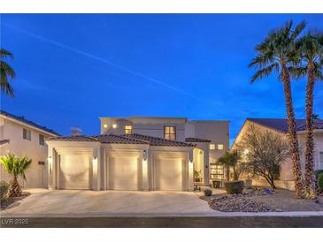 Charming two-story stucco home featuring a three-car garage and desert landscaping at twilight at 8032 Marbella Cir, Las Vegas, NV 89128