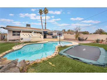Backyard pool with lush grass, palm trees, and a trampoline. Perfect for summer fun at 212 N Torrey Pines Dr, Las Vegas, NV 89107