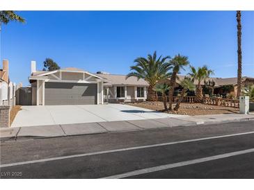 Charming single-story home featuring a two-car garage, palm trees, and a well-manicured front yard at 3916 S Torrey Pines Dr, Las Vegas, NV 89103