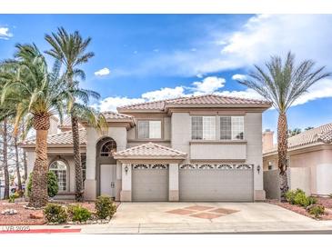 Stunning two-story home featuring a three-car garage and beautiful desert landscaping with palm trees at 4679 El Camino Cabos Dr, Las Vegas, NV 89147