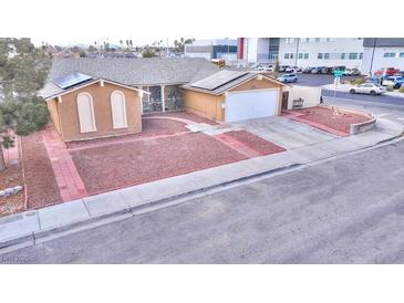 Charming single-story home with a gravel yard, solar panels, and a paved driveway leading to a two-car garage at 4735 Monterrey Ave, Las Vegas, NV 89121