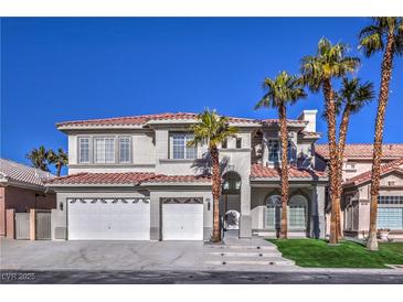 Stunning two-story home with a three-car garage and meticulously landscaped front yard with palm trees at 8864 La Manga Ave, Las Vegas, NV 89147