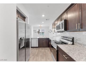 Beautiful kitchen featuring stainless steel appliances, granite countertops, and dark wood cabinetry at 12367 Indigo Montage Rd # 3, Las Vegas, NV 89183
