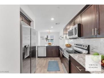 Modern kitchen featuring stainless steel appliances, granite countertops, and dark wood cabinetry at 12367 Indigo Montage Rd # 3, Las Vegas, NV 89183