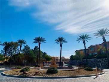 Beautiful community entrance features a water fountain, desert landscaping, and towering palm trees at 3525 Hammock St, Las Vegas, NV 89147