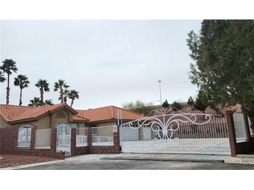 Charming single-story home featuring a terra cotta roof, desert landscaping and gated entry way at 1163 Spanish Armada Rd, Las Vegas, NV 89123