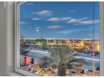 Stunning Las Vegas city view from a large window overlooking palm trees and surrounding neighborhood at twilight at 1486 Neyland Dr, Henderson, NV 89012