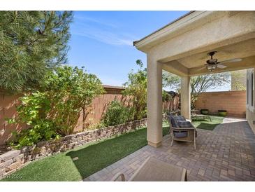 Relaxing covered patio area features brick pavers, artificial grass, and comfortable seating for enjoying the outdoors at 168 Springhouse St, Las Vegas, NV 89148