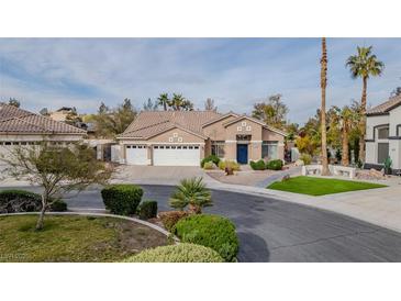 Charming single-story home with a three-car garage, desert landscaping, and a welcoming blue door at 1720 Sand Storm Ct, Henderson, NV 89074