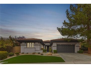 Charming single-story home boasts mature landscaping, gray stucco, and a two-car garage at 26 Moraine Dr, Henderson, NV 89052