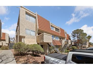 Exterior view of a multi-level townhome with textured walls, red roof tiles and a well maintained landscape at 3597 Arville St # 201B, Las Vegas, NV 89103