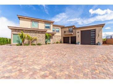 Stunning exterior with brick driveway, stone accents, a three car garage, and a private balcony at 386 Cactus River Ct, Henderson, NV 89052
