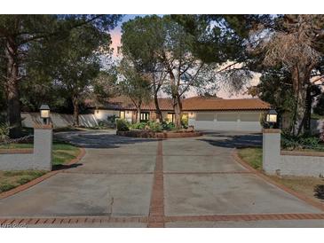 Expansive home featuring a circular driveway, mature trees, and three-car garage at 6998 Alamitos Cir, Las Vegas, NV 89120