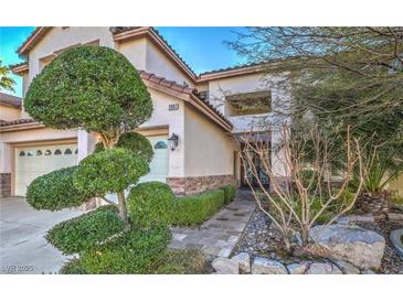 Charming stucco home featuring a manicured front yard with decorative landscaping and a two-car garage at 2007 Trailside Village Ave, Henderson, NV 89012