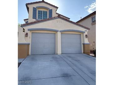 Attached two-car garage with gray doors and concrete driveway on a stucco two-story home at 2431 Lilac Cove St, Las Vegas, NV 89135