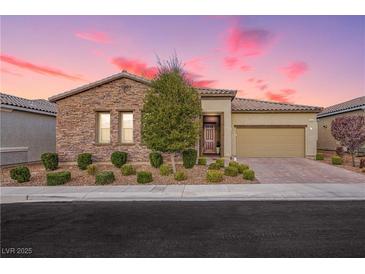 Charming single-story home with a stone facade, manicured landscaping, and a two-car garage at sunset at 2450 Amatrice St, Henderson, NV 89044