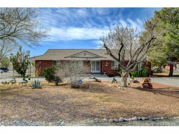 Charming brick home with desert landscaping and mature trees on a sunny day at 3140 Unicorn Ave, Pahrump, NV 89048