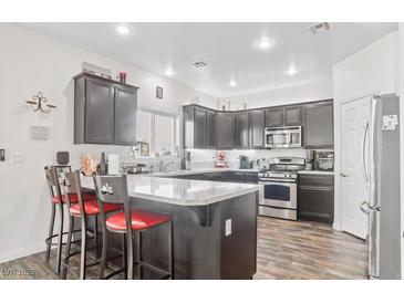 Modern kitchen features granite countertops, dark cabinetry, stainless steel appliances, and an island with seating at 3632 Julia Waldene Ct, Las Vegas, NV 89129