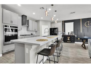 Modern kitchen features a large island with bar seating, pendant lights, and stainless steel appliances at 4588 Swimming Minnow Ave, Las Vegas, NV 89141
