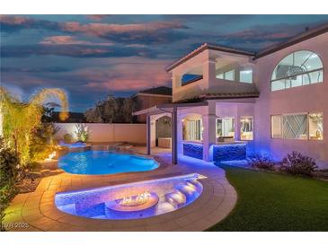 Inviting pool area featuring a waterfall, a fire pit, and an outdoor bar with stylish blue accent lighting at 6655 Tranquil Seas Ct, Las Vegas, NV 89139