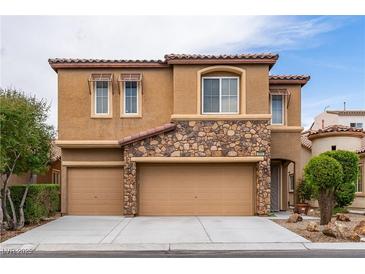 Charming home with a tan stucco exterior, stone accents, three-car garage, and well-maintained landscaping at 9869 White Lilac St, Las Vegas, NV 89178