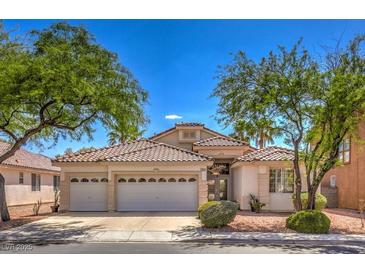 Charming home featuring a three-car garage, desert landscaping, and a tile roof in a lush setting with mature trees at 1363 Rolling Sunset St, Henderson, NV 89052