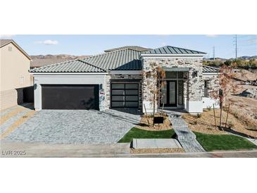 Beautiful single-story home with a stone facade, black garage door, and paved driveway at 311 S Lisbon St, Henderson, NV 89015