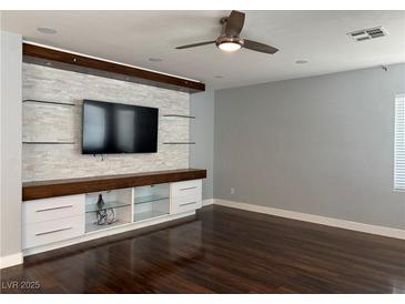 Bright living room featuring a large built-in entertainment center with shelving and hardwood floors at 4912 Capo Gallo St, Las Vegas, NV 89130