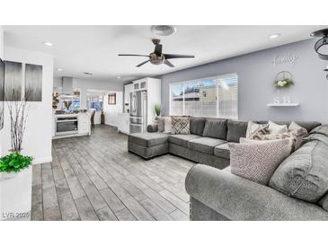 Open concept living room featuring a comfortable gray couch, modern ceiling fan, and wood-look floors at 5582 Tunis Ave, Las Vegas, NV 89122