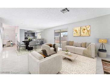 Bright living room with stylish furnishings, neutral tones, and sliding glass door to backyard at 5815 Christchurch Ave, Las Vegas, NV 89110