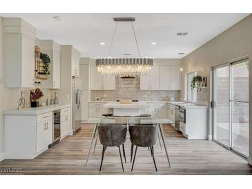 Bright kitchen features white cabinets, stainless steel appliances, a large island, and an elegant chandelier at 2033 Shining Feather Ln, Las Vegas, NV 89134